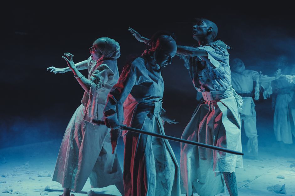 Artists perform in dramatic lighting, showcasing dance and theater with expressive costumes